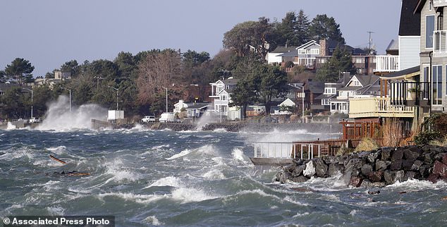 Waves crashed near homes at high tide during a windstorm Thursday in Seattle. More than 140,000 households and businesses lost power Thursday as strong winds toppled trees