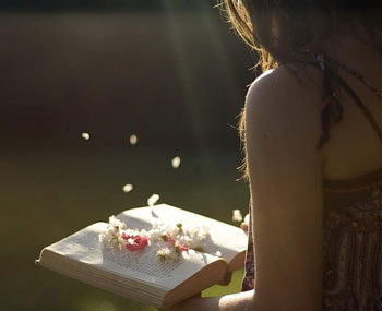 Девушка держит книгу с лепестками