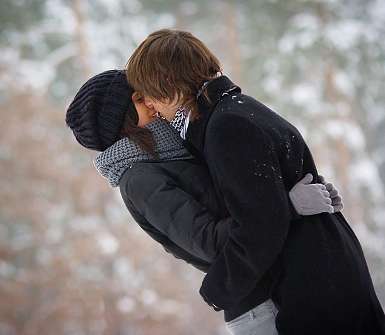 Парень целует девушку на улице зимой