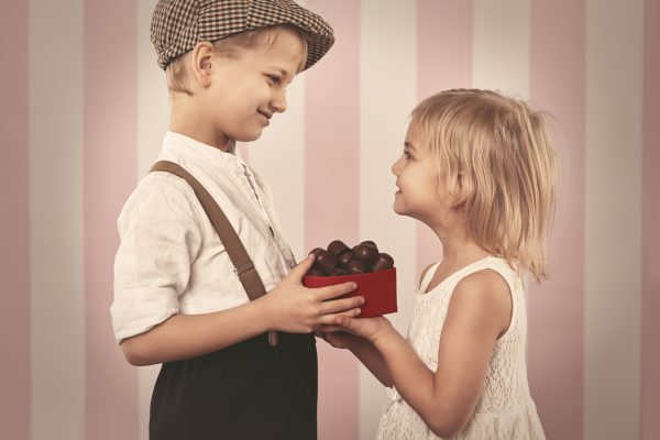 Мальчик дарит девочке конфеты