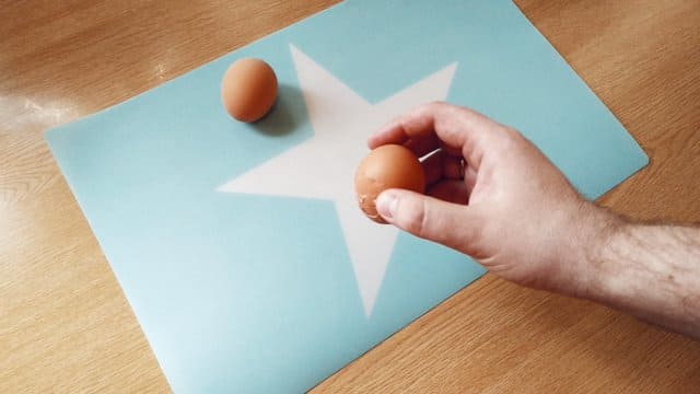 рука и яйцо возле стола