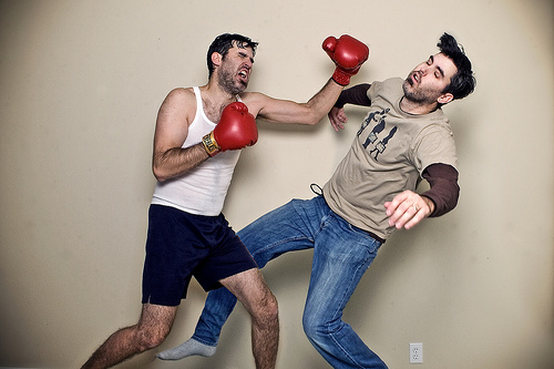 Мужчина избивает приятеля в боксерских перчатках.